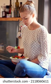 Feeling Good Starts With Eating Right. Shot Of A Young Woman Eating A Healthy Salad In Her Kitchen.