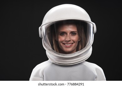 Feeling happiness. Portrait of charming delighted female astronaut wearing helmet and protective suit is standing and looking at camera with wide smile. Isolated background - Powered by Shutterstock