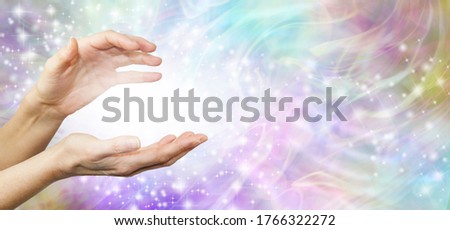 Feeling Healing Energy Between Hands - a pair of female hands with a white energy orb between on an ethereal pink and purple  energy field background 
