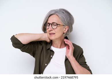 Feeling Neck Or Back Pain, Herniated Disc Mature Grey Haired Woman Touching Her Back Neck. Upset, Frustrated Senior Woman Hold Her Neck Suffering From Pain Isolated On White Background.