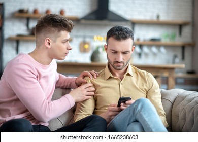 Feeling Sad. Man In Orange Shirt Feeling Upset While His Friend Taping His Shoulder