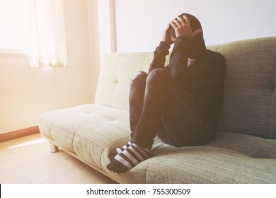 Feeling stressed. Frustrated handsome young man touching his head and keeping eyes closed while sitting on the couch at home.soft focus