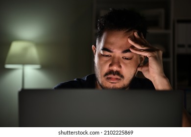 Feeling Stressful And Depressed. Asian Man Feeling Looking Unhappy, Stressed And Tired While Using Computer Working Late At Night At Home