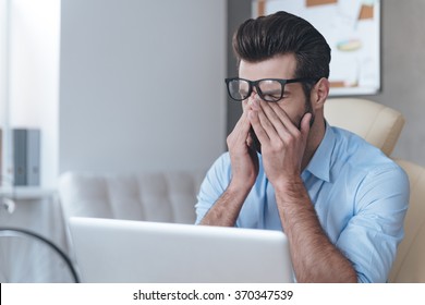 Feeling Tired. Frustrated Young Handsome Man Looking Exhausted And Covering His Face With Hands While Sitting At His Working Place 