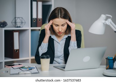 Feeling Tired and Stressed. Frustrated Young Woman Keeping Eyes Closed and Massaging Nose While Sitting at Her Working Place in Office. Young Businesswoman is Tired and Feels Stressed Out