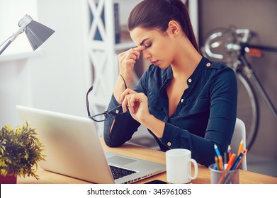 Feeling tired and stressed. Frustrated young woman keeping eyes closed and massaging nose while sitting at her working place in office - Shutterstock ID 345961085