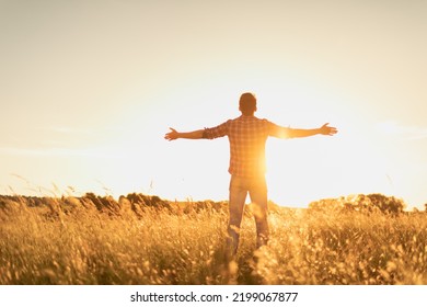 Feelings of hope, power and freedom in nature. Young man standing in a field with arms up feeling the rays on the warm sunshine light. Mind body spirit concept.  - Powered by Shutterstock