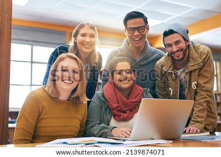 It feels a bit better when youre studying together. Portrait of a cheerful young group of students working together using a laptop to study for exams inside of a library.