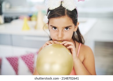 It feels like Im doing all the work. Shot of an adorable little girl blowing up a balloon at her birthday party.