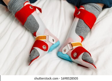 feet of a 5-year-old boy with orthopedic splints to learn how to walk, foot support, leg prosthesis. the mother or physical therapist is putting them on for therapeutic exercises.