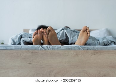 Feet Of African American Couple On Bed