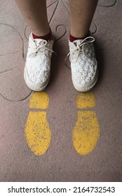 Feet And Arrows On Road. Yellow Straight Arrow Sign And White Shoes. Straight Direction Concept. Journey Concept

