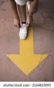 Feet And Arrows On Road. Yellow Straight Arrow Sign And White Shoes. Straight Direction Concept. Journey Concept

