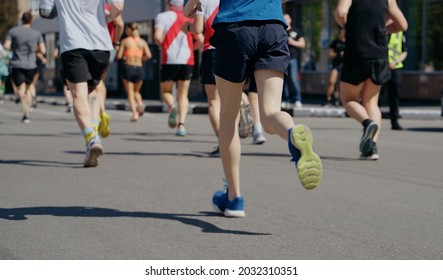 Feet Of Athletes Running Marathon In City, Onlookers On Roadside. Partial View From Behind Of Contestants Of Sports Event. Healthy Lifestyle. Concept Of Sport