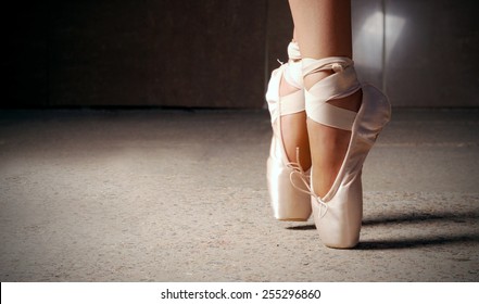 Feet of ballerina dancing in ballet shoes over a dark background