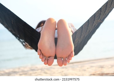 Feet of a beautiful woman. She lies in a hammock on the beach of the sea. In the summer she feels the good weather. she is on vacation - Shutterstock ID 2151997575