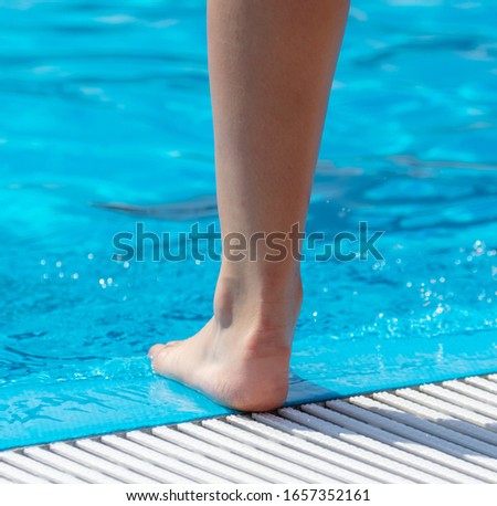 Feet in the blue water of the pool. Holiday at the resort