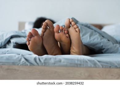 Feet Of Blurred African American Couple On Bed