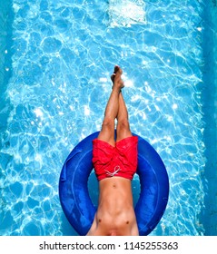 Feet And Body Of A Man In The Pool On A Swim Tube, Inner Tube, Red Swimming Trunks