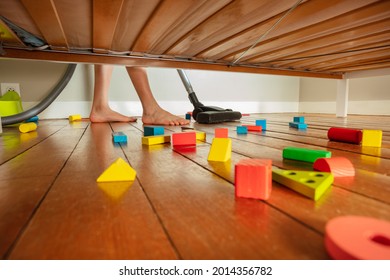 Feet Of Boy Cleaning Floor Of His Room View Under The Bed Full Of Toys