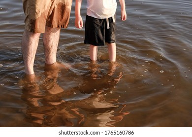 feet of a boy and a man in the water near the sea