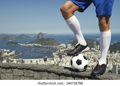 Feet of Brazilian soccer player standing with football above Rio de Janeiro skyline with Sugarloaf Mountain