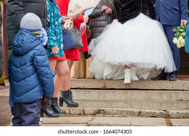 Feet Of The Bride And Groom Outdoors. A Girl In White Shoes And A Man In Black Shoes Before The Wedding Ceremony Outside In A Cold Day