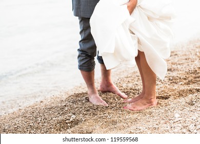 The feet of the bride and the groom playing on the beach.