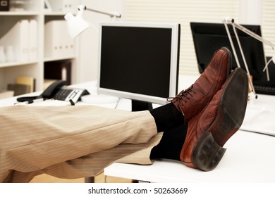 Feet Of A Businessman On The Table In His Office