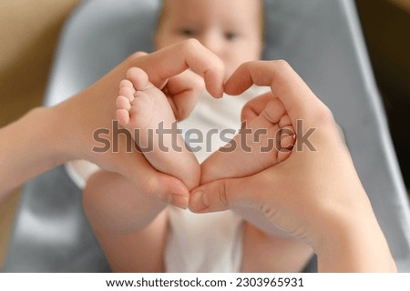 Feet of the child in the hands of the mother in the shape of a heart, close-up. Mother love,maternity leave, motherhood.