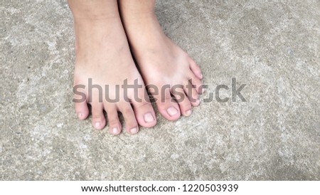 The feet of children and adults on the cement floor.