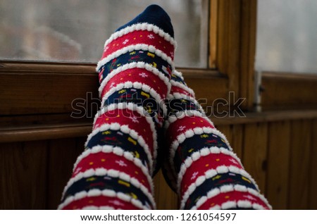 Feet in Christmas socks.  Girl relaxing at home. Winter holiday Xmas and New Year concept.  Feet Woolen Socks By Window.