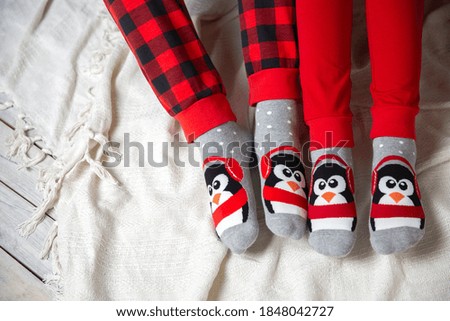 Feet in Christmas socks on a white blanket. A couple, relaxing, warming their feet in wool socks. Concept of winter and Christmas holidays