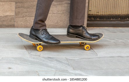 Feet Of A Confident Business Man With Formal Attire On Riding A Skateboard Over City Footpath