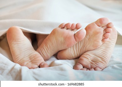 Feet Of Couple In The Bed