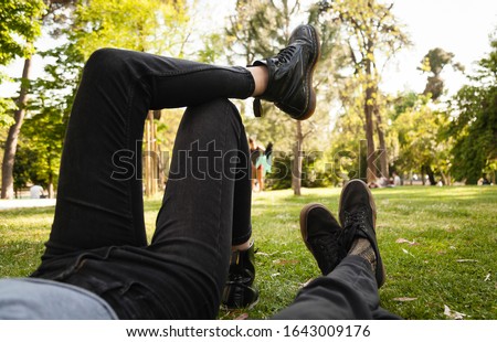 Feet of a couple lying on a park grass  crossing legs confortable during a Valentine´s day date on a sunny day. Summer or spring lovers concept.