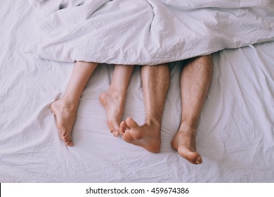 Feet of couple side by side in bed 