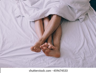 Feet Of Couple Side By Side In Bed 