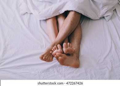 Feet Of Couple Side By Side In Bed