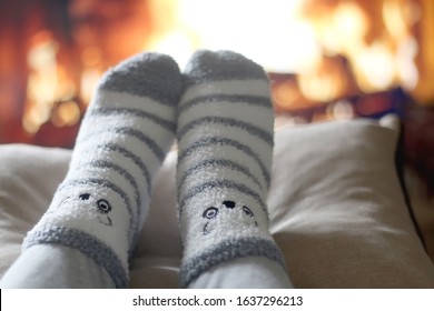 Feet in cute fuzzy socks in front of a fireplace. Selective focus.
