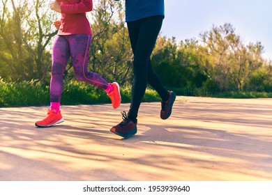 Feet Detailed Shot Of Two Person Running Outside. Colorful Bright Sportswear. Unrecognizable Person.