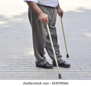 The feet of an elderly man disabled with a cane.