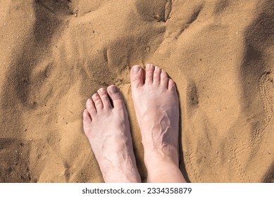 feet of an elderly woman standing on the hot sand