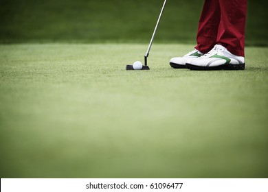 Feet of female golf player putting at green, with plenty of copy-space. - Powered by Shutterstock