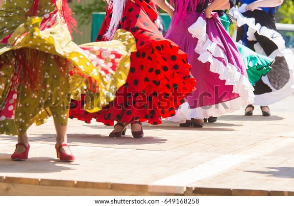 Feet of flamenco dancers, performing on a wooden\
stage in summer city\
festival