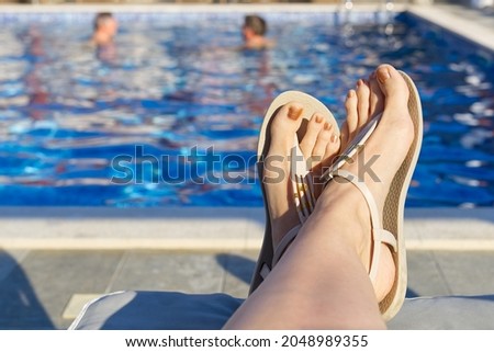 feet in front of blue water in open swimming pool in summer sunny day