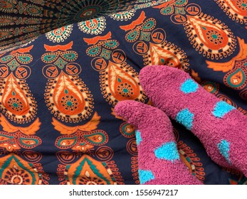 Feet In Fuzzy Socks In Front Of Patterned Background.