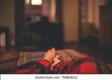 Feet of the girl lying on the sofa in the warm cozy room - Powered by Shutterstock