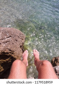 Feet Hanging Off Cliff Over Ocean Clear Water In Nice France