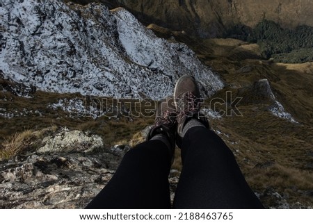 Feet hanging off a drop of a mountain whilst hiking, new zealand